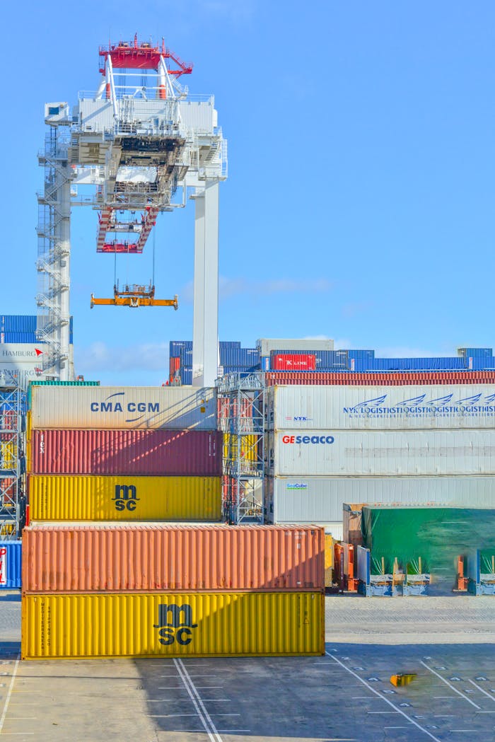 services-03 Stacked cargo containers in a sunny port industrial setting with crane.