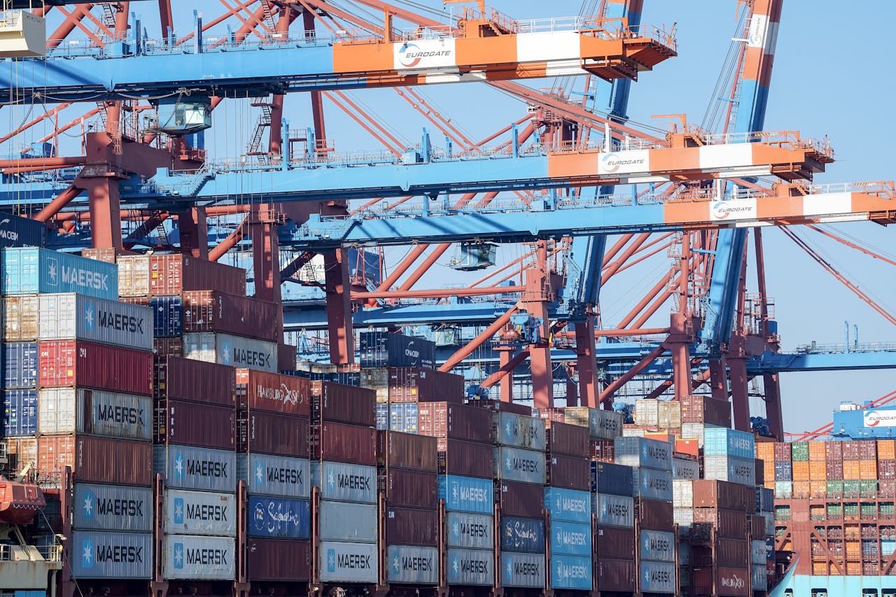 A bustling view of the Hamburg port showing cranes and stacked shipping containers.