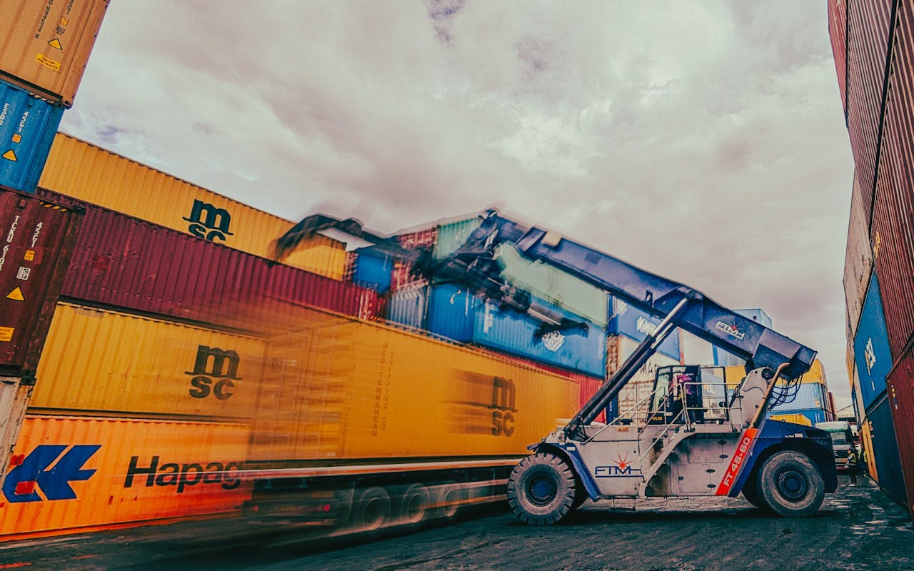 contact-img Dynamic scene of containers being loaded by a crane in an industrial shipping yard.